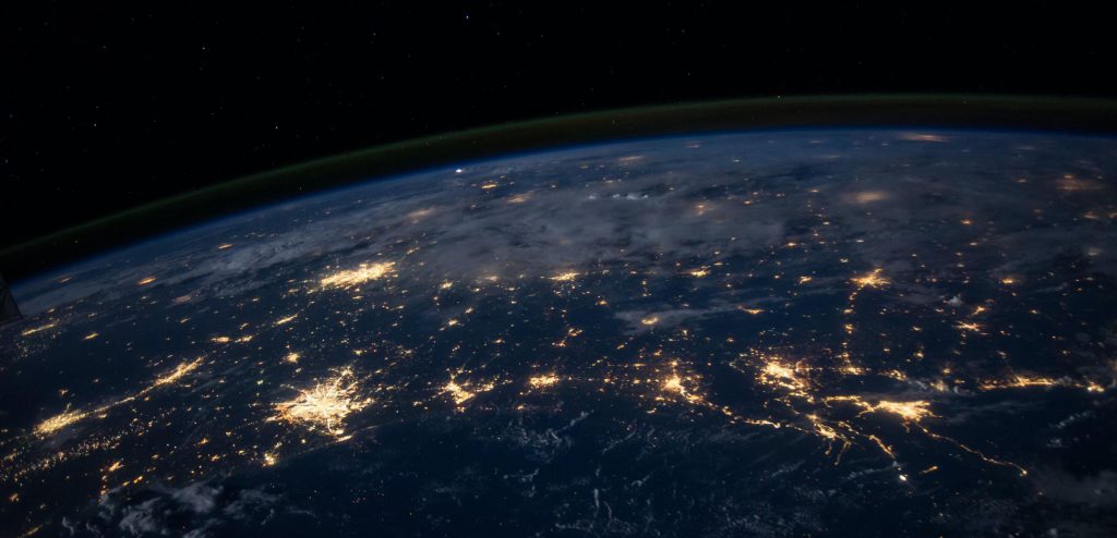 Image of Earth from space at night, showing city centers with well-lit points throughout globe